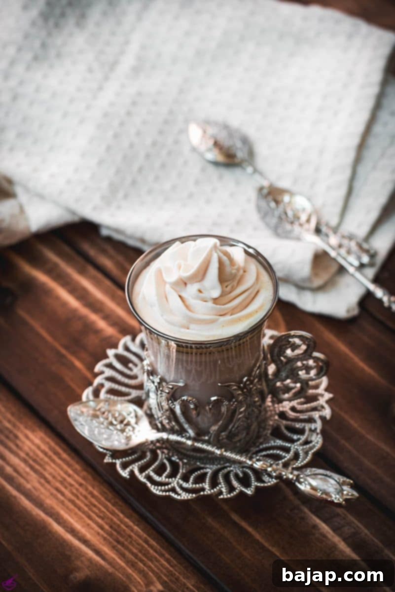 Medieval glass mug, filled with delicious strawberry white hot chocolate and topped with strawberry-flavored whipped cream.