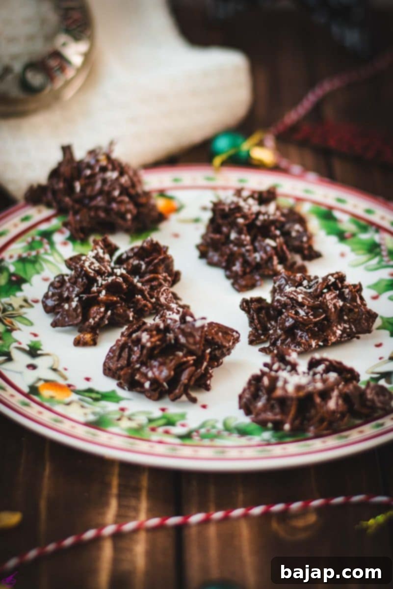 Christmas plate filled with dark chocolate clusters, on brown wooden background, next to Christmas decorations.