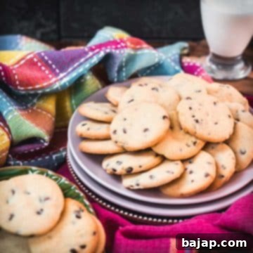 Chocolate chip sugar cookies placed on pink plates, embedded in colorful tea towels, in front of a glass of milk, a perfect snack.