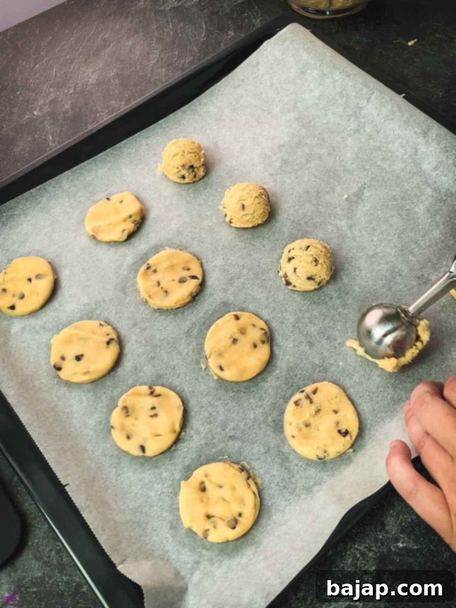 Scoop out the cookie dough into uniform balls, placing each on a baking sheet lined with parchment paper, preparing for the next step.