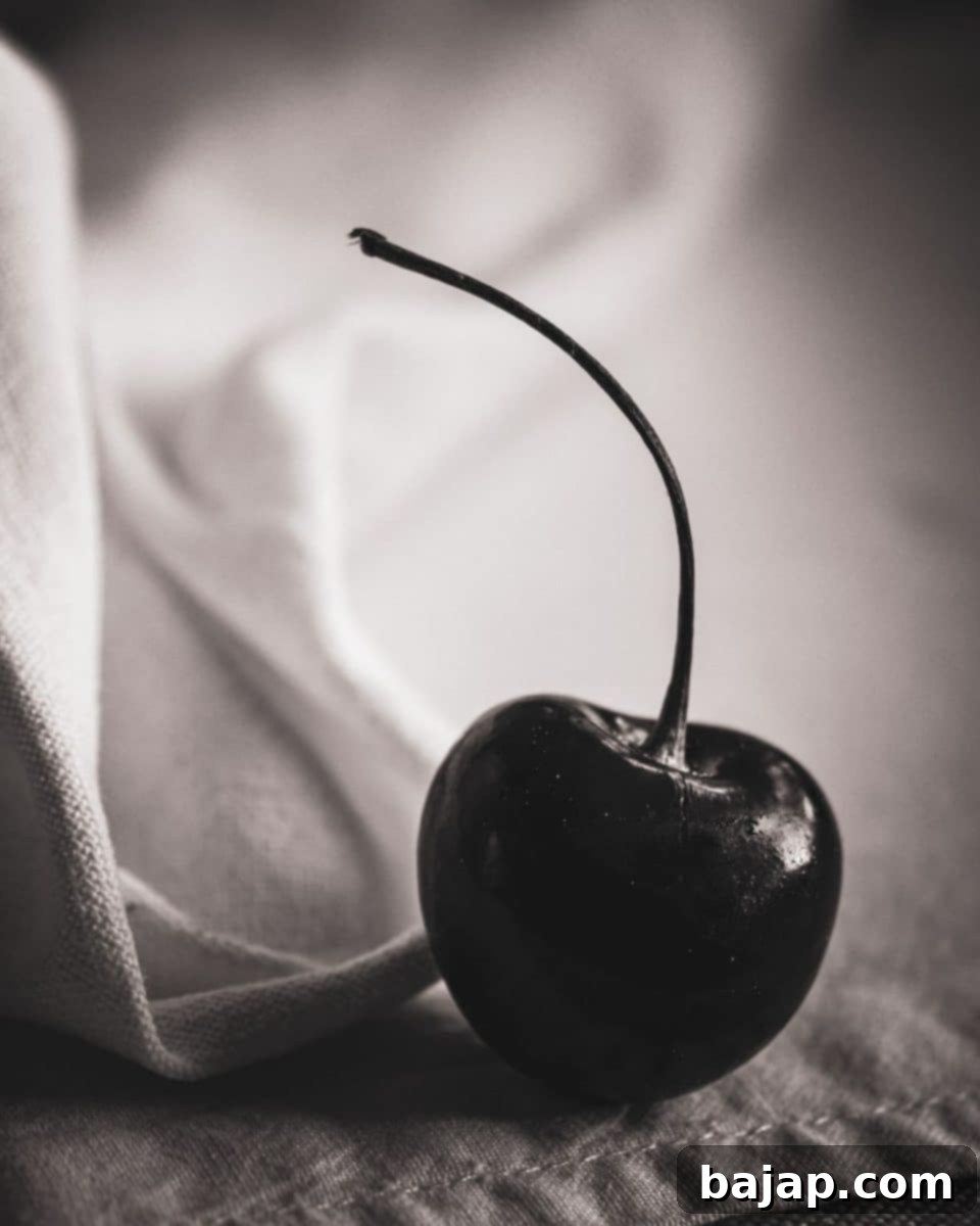 Close-up of three black and white marasca cherries on a stem, highlighting their natural beauty and origin.