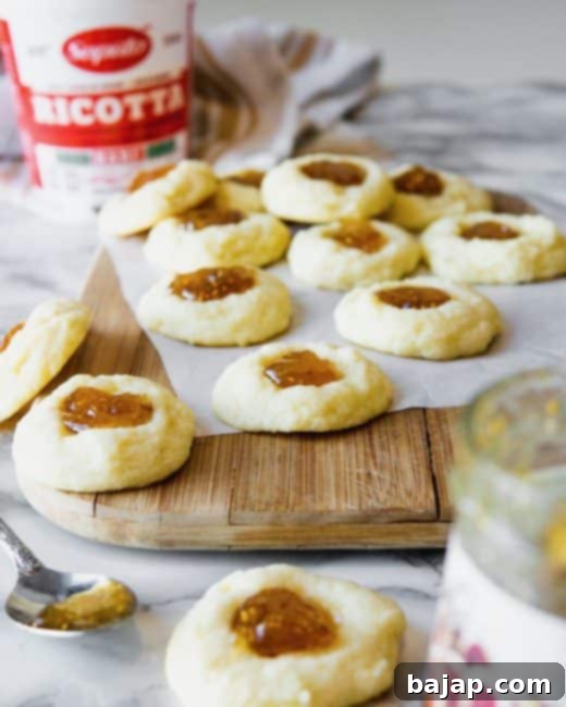 Soft, cake-like ricotta cookies with a dollop of bright fig jam on top, arranged on a beautiful serving tray.
