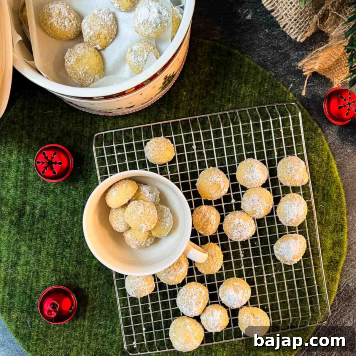 Melt-in-your-mouth butterball cookies on placed on cooling rack next to tea cup filled with butterball cookies.