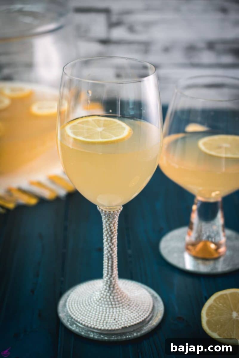 Sparkling Citrus Celebration 2 Two elegant glasses filled with sparkling lemon punch, garnished with a vibrant lemon slice and a fresh mint leaf, set on a reflective mirror coaster, ready for a New Year's toast.
