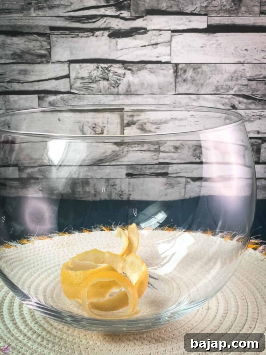 Sparkling Citrus Celebration 3 A pristine glass punch bowl on a white table mat, elegantly filled with spirals of fresh lemon zest, ready for the infusion process.