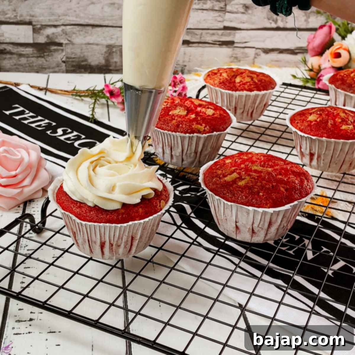 Fluffy Cream Cheese Frosting for Red Velvet Delights 4 Piping cream cheese frosting on top of red velvet muffin.