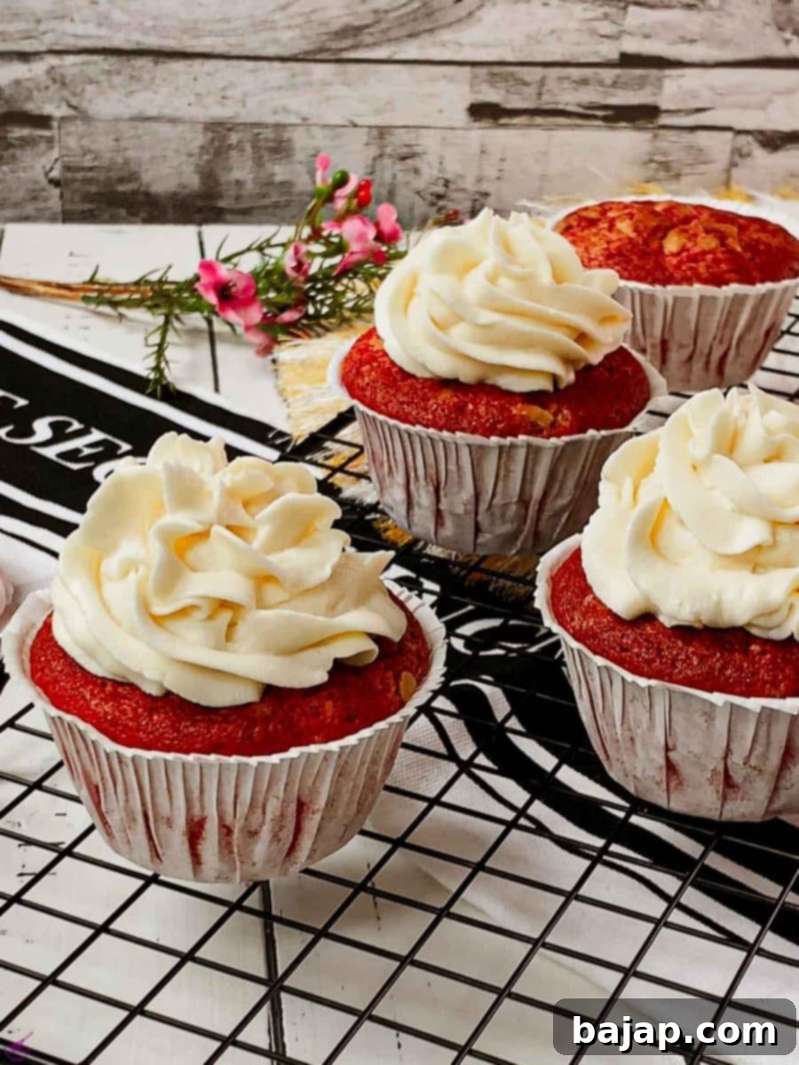 Fluffy Cream Cheese Frosting for Red Velvet Delights 6 Cream cheese frosting on top of red velvet muffin placed on cooling rack.