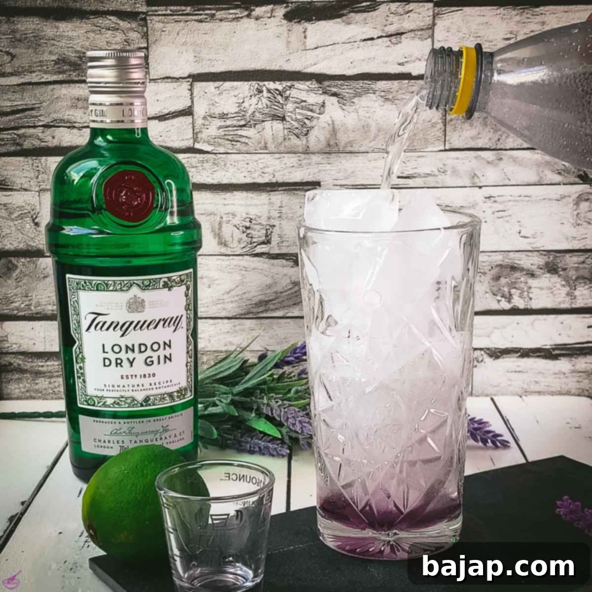 Lavender Gin and Tonic: Your Guide to Botanical Bliss 6 Filling a lavender gin and ice cube filled highball glass with tonic water.