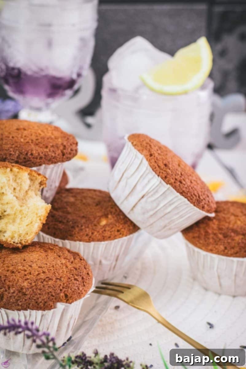 Delicious lavender lemon muffins on a clear glass tray, showcasing their golden tops and delicate crumb. The subtle floral aroma of lavender combined with the zesty tang of lemon creates a delightful flavor explosion in every bite, making these a must-try for any baking enthusiast.