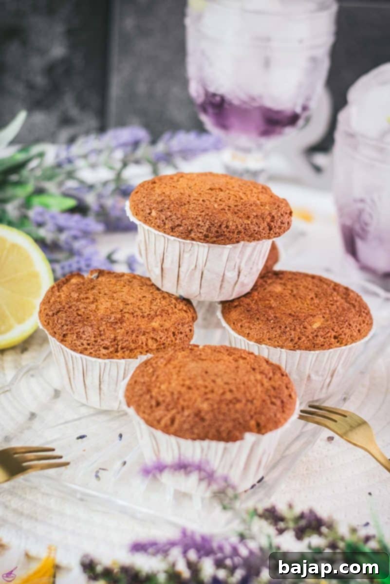 Exquisitely arranged delicious lavender lemon muffins on a sleek glass tray, ready to be served. Each muffin showcases a delicate golden crust and the inviting allure of its floral and citrus notes, making them perfect for a refined dessert or a delightful breakfast treat.
