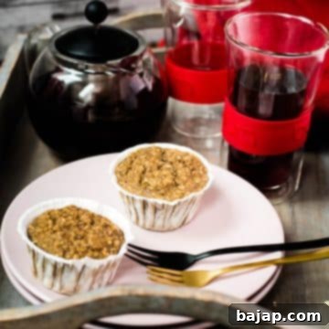 Two delicious banana oatmeal muffins on pink plate placed on wooden tray. Behind it, red fruit tee.