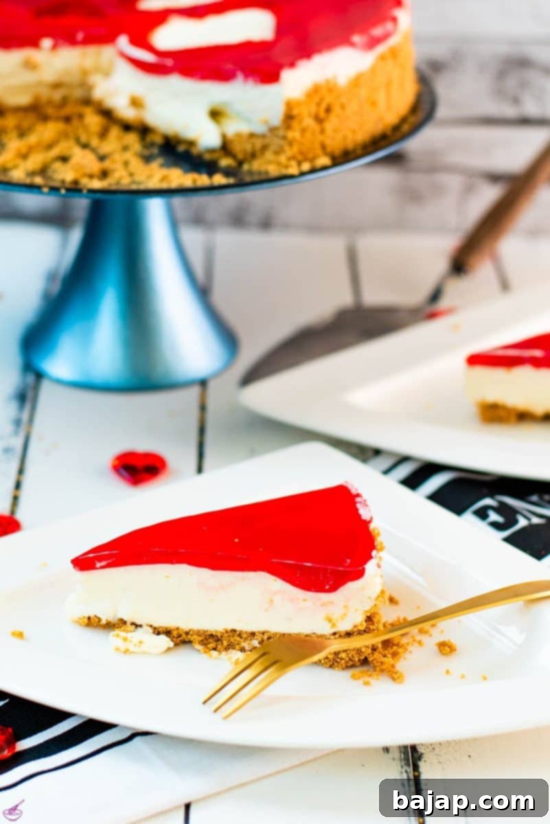 A slice of delicious Valentine's Raspberry Cheesecake placed on white plate next to a golden fork.