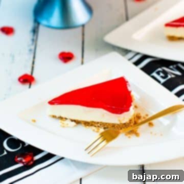 A slice of delicious Valentine's Raspberry Cheesecake placed on white plate next to a golden fork.