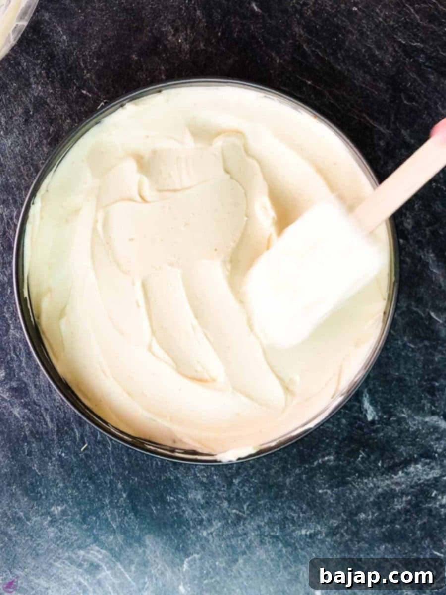 Spread the cream cheese filling evenly on top of the graham cracker crust.