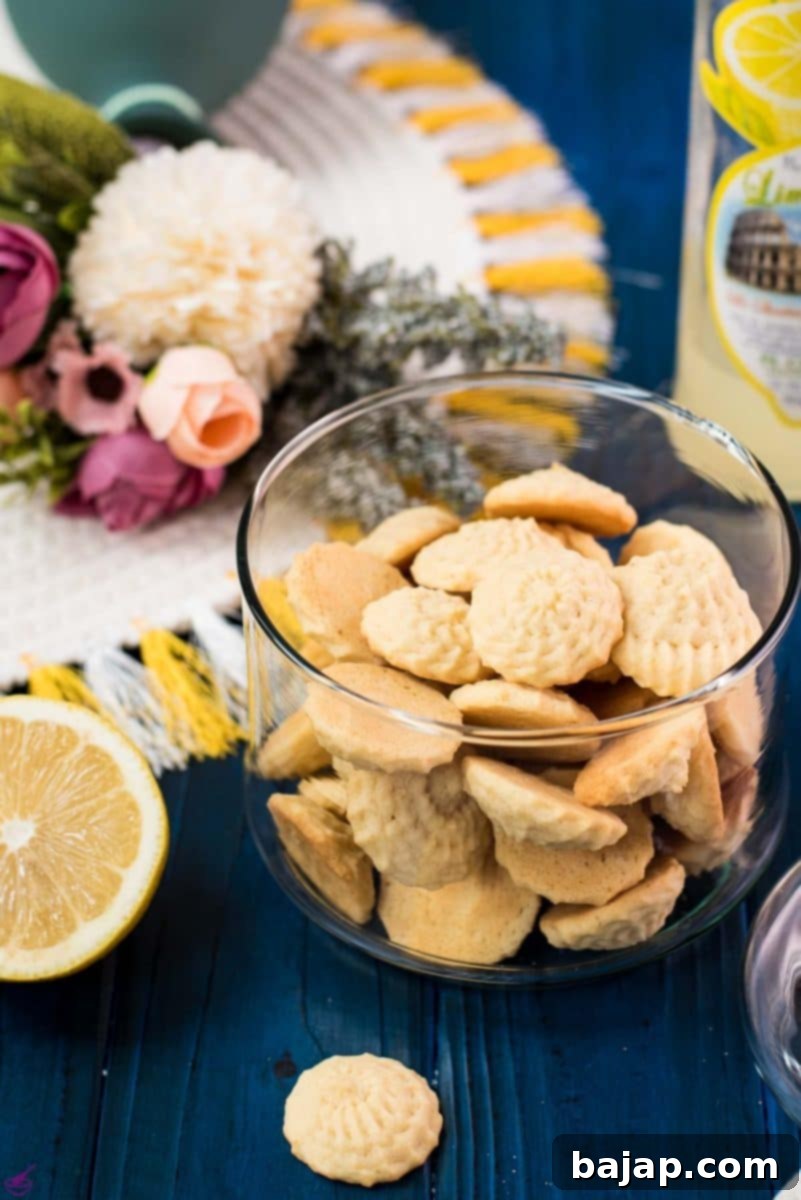 Gorgeous mini lemon sugar cookies placed in a glass jar on a blue wooden ground.
