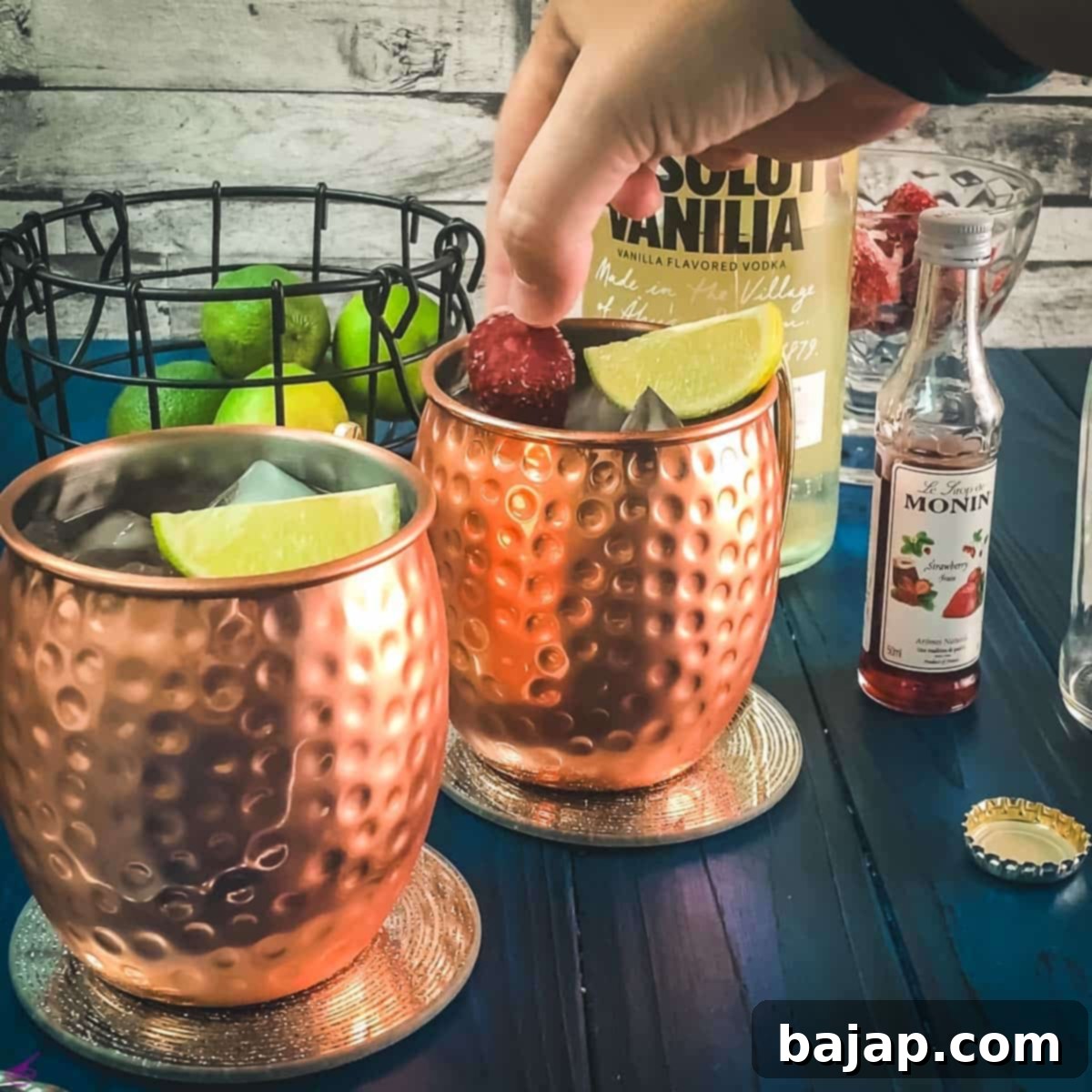 Garnishing the strawberry Moscow mule with a lime wedge and frozen strawberries.