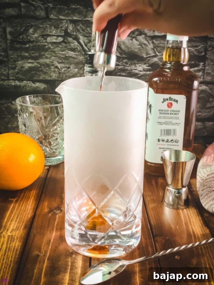 Three dashes of Angostura bitters being added into the chilled stirring glass.