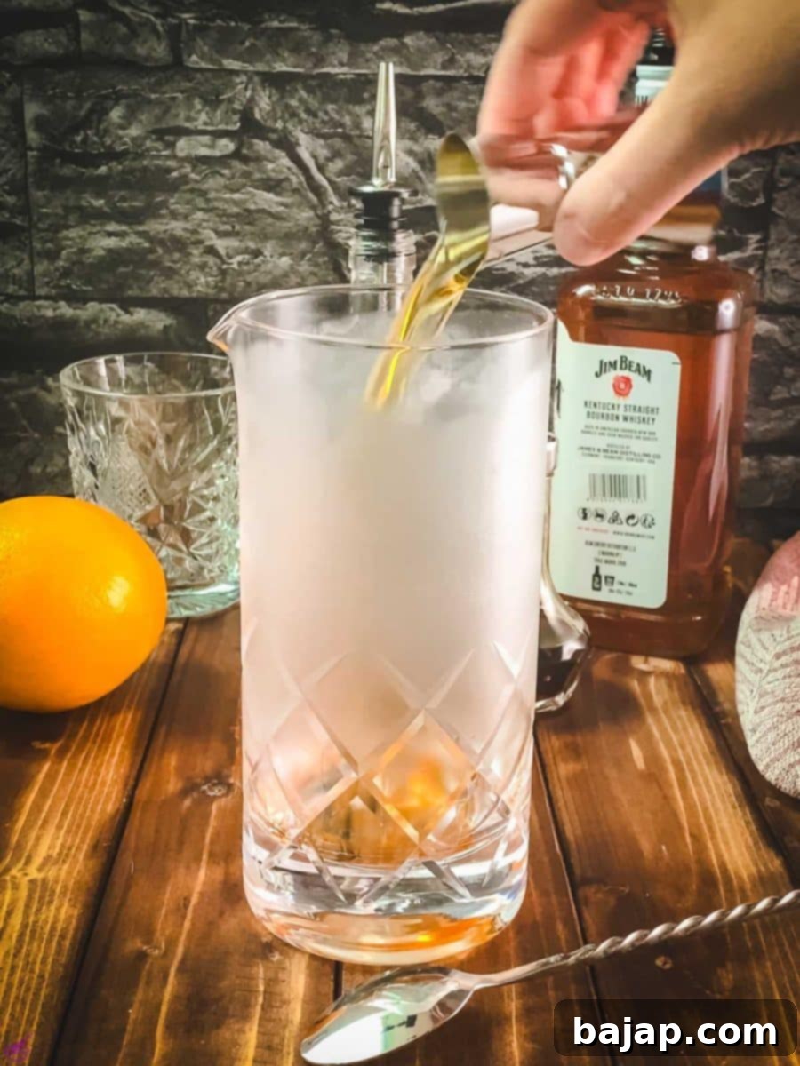 Adding bourbon into the stirring glass with the other ingredients.