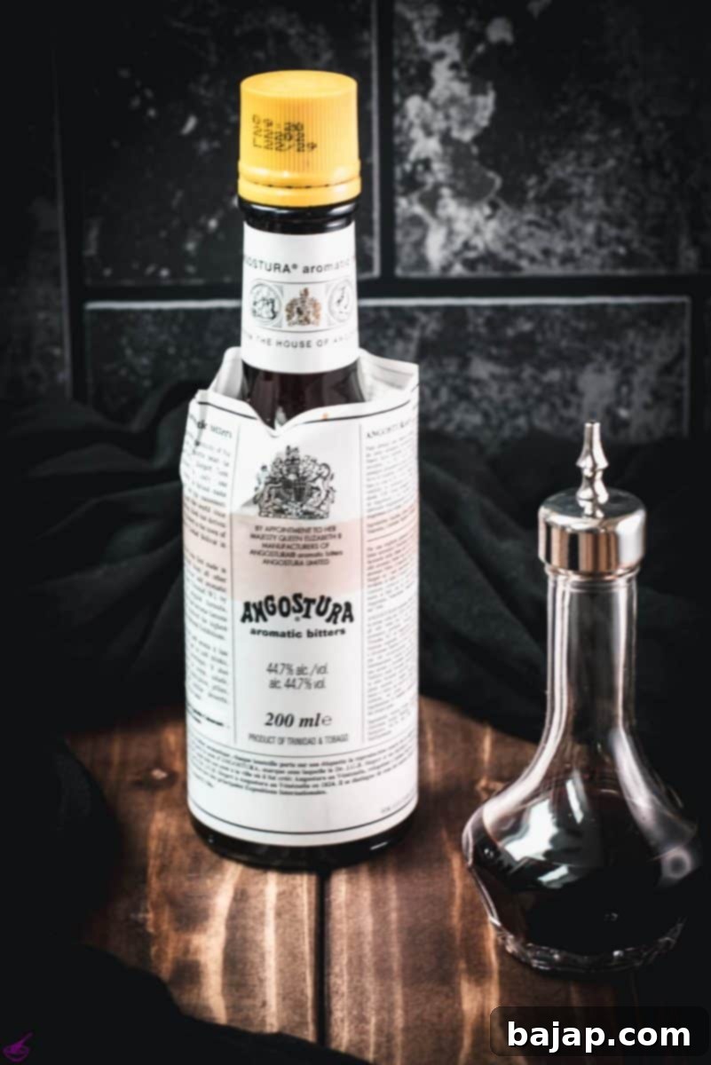 One bottle and one dasher with angostura bitters placed on wooden ground.