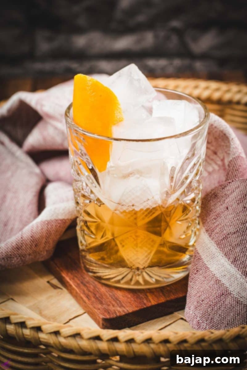 Gorgous glass filled with a delicious old fashioned drink. Placed on wooden coaster.