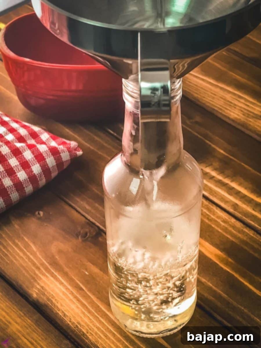 Using a funnel, the sugar syrup is poured into a bottle.