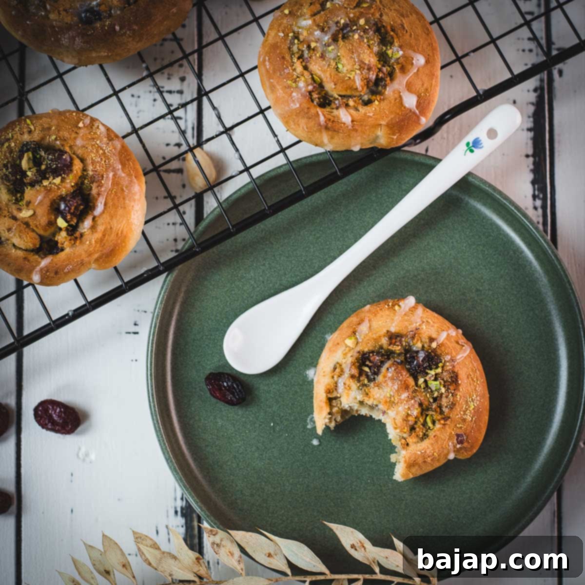 A delicious, half-eaten mini pistachio sweet roll on a green plate.