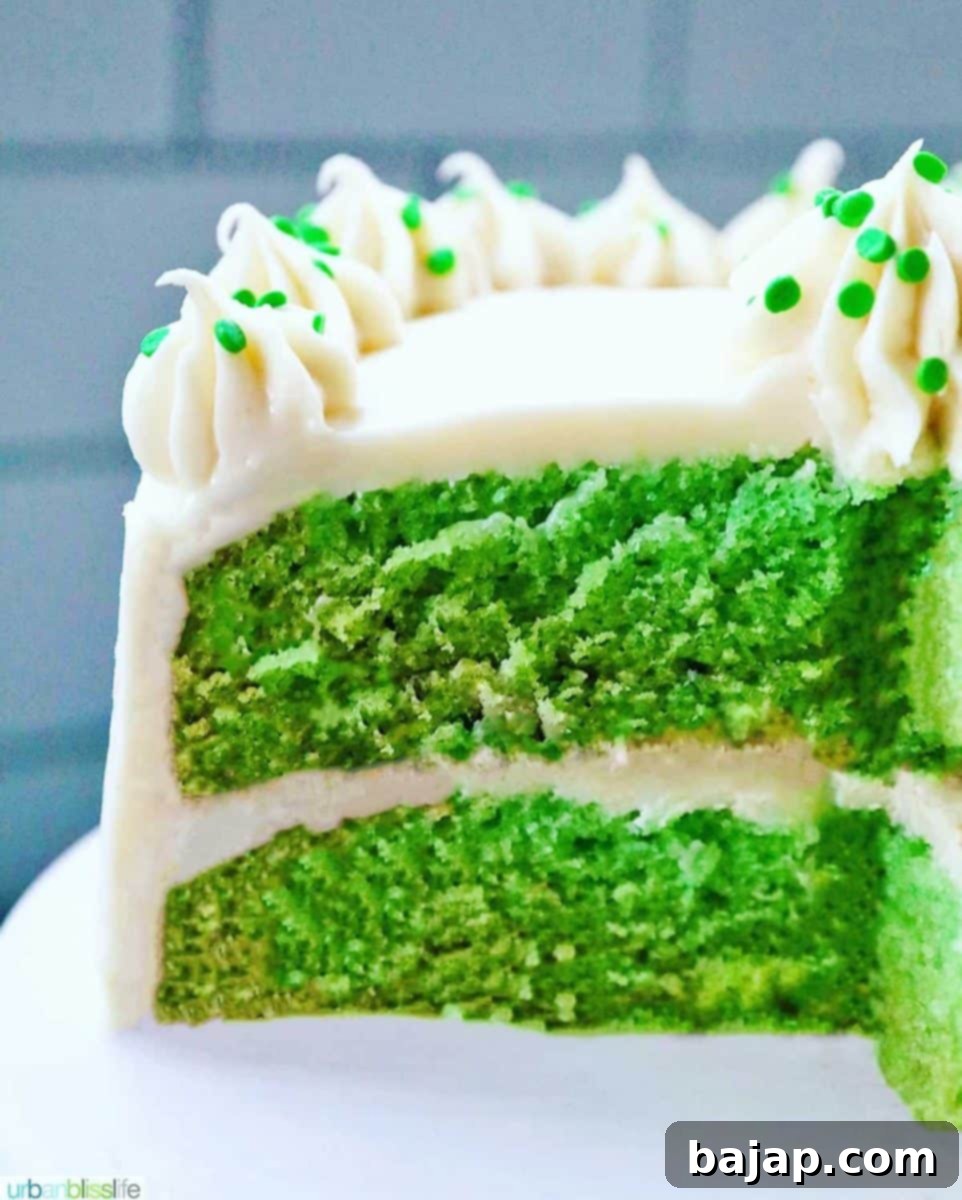 A stunning slice of Green Velvet Cake, revealing its vibrant green layers and luscious cream cheese frosting, perfect for any celebration.