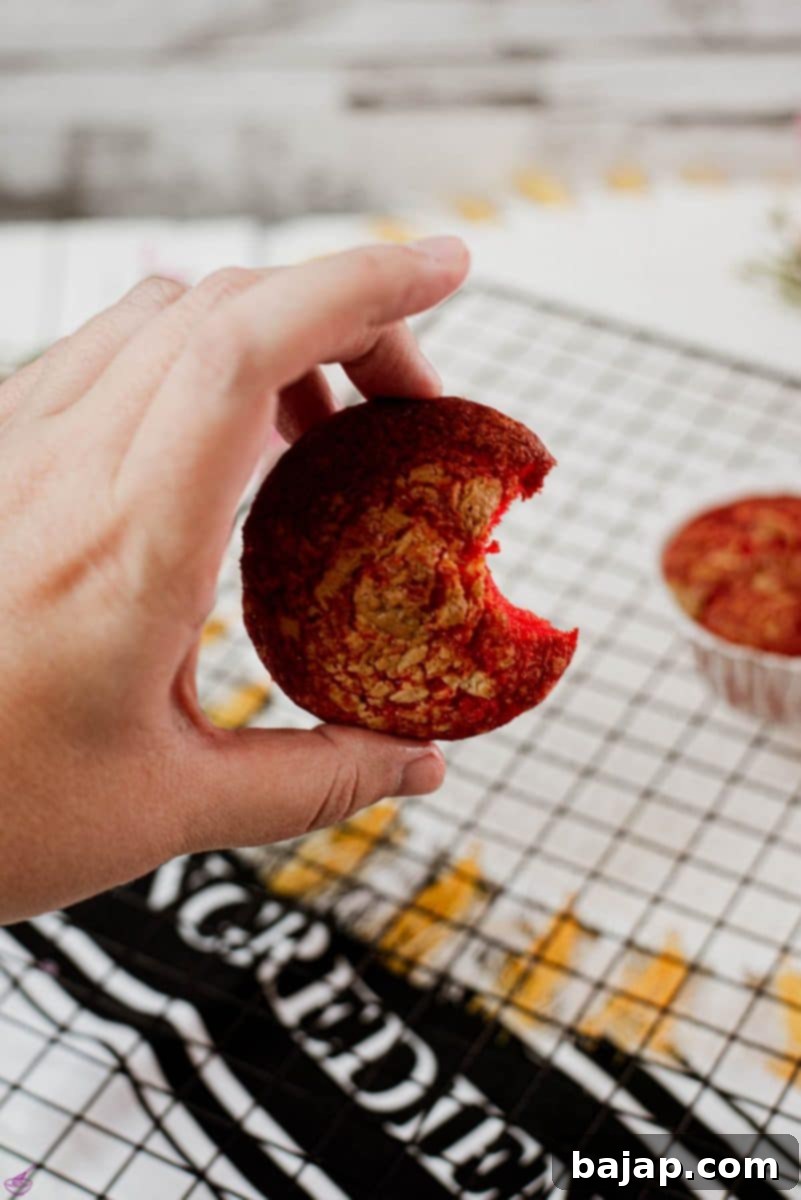 A gorgeous red velvet sponge cupcake with a bite taken out, revealing its incredibly moist, tender, and evenly colored interior.