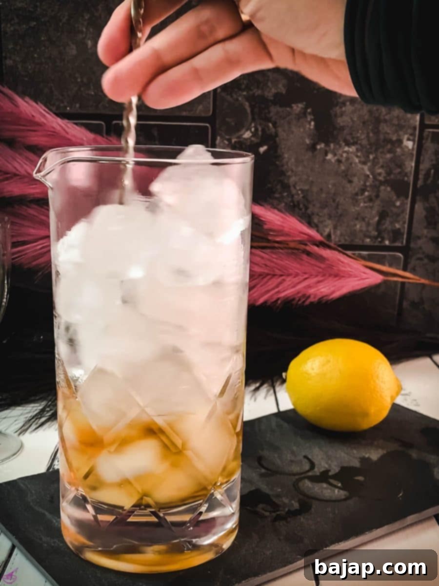 Gently stirring the Martinez cocktail mixture with a bar spoon to properly chill and dilute the spirits, essential for a smooth finish.