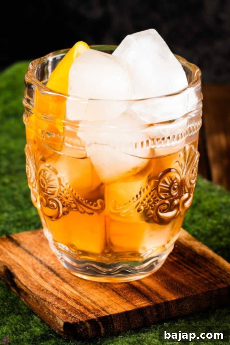 Golden Maple Old Fashioned 11 Gorgeous glass filled with maple old fashioned on wooden coaster. The drink is garnished with an orange zest.