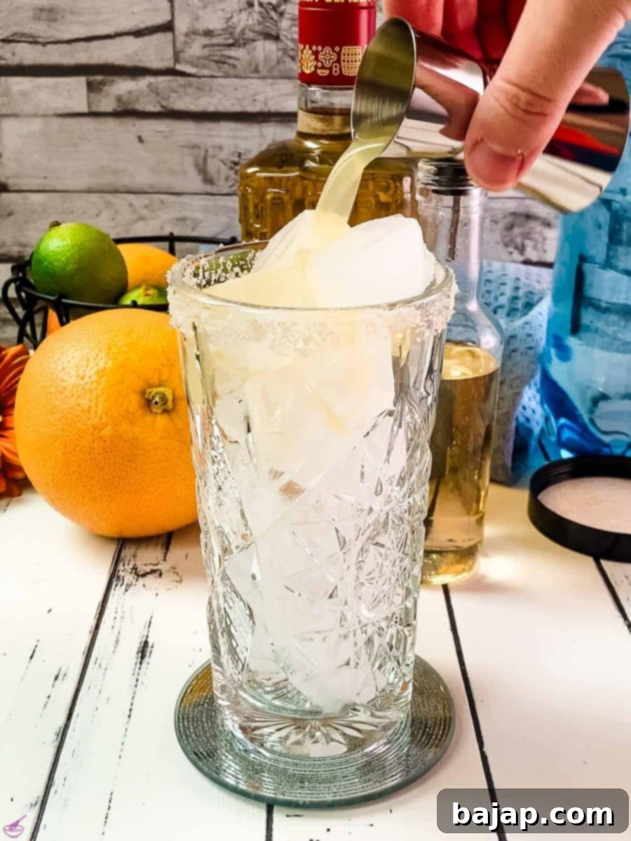 Add freshly squeezed lime juice into the ice-filled highball glass, introducing a vibrant citrus note.
