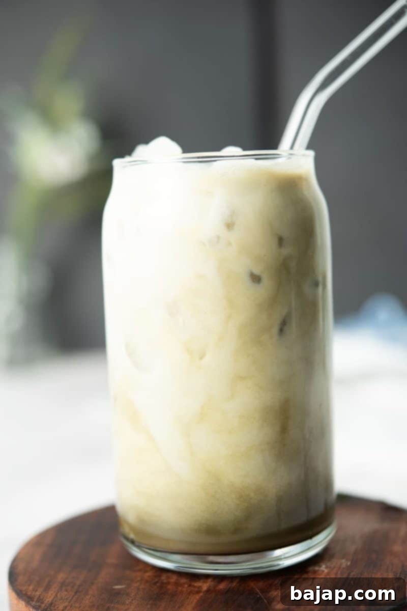 Glass with Matcha oat milk latte and glass straw.