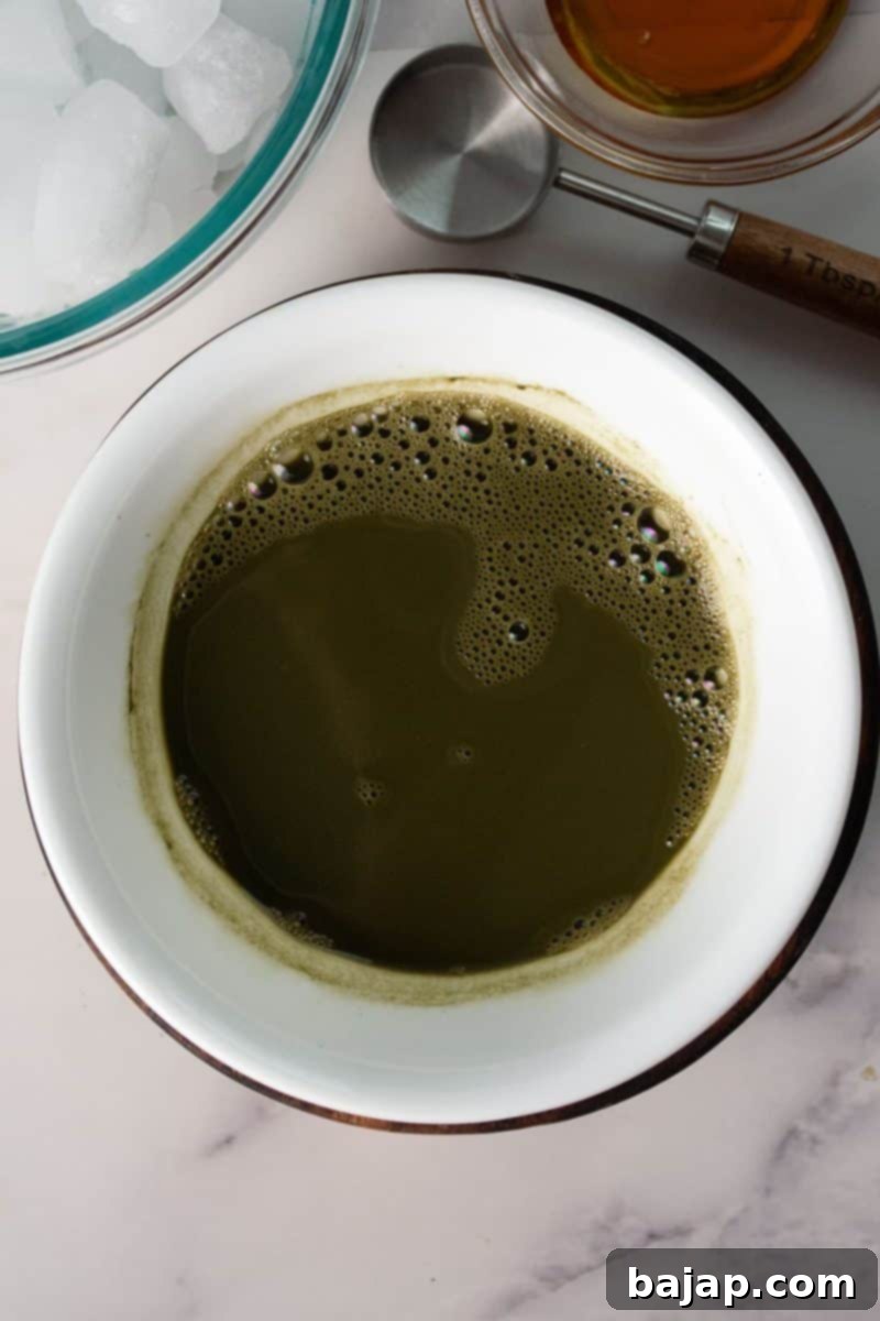 Overhead view of a bowl filled with smoothly whisked matcha and water, ready for latte preparation.