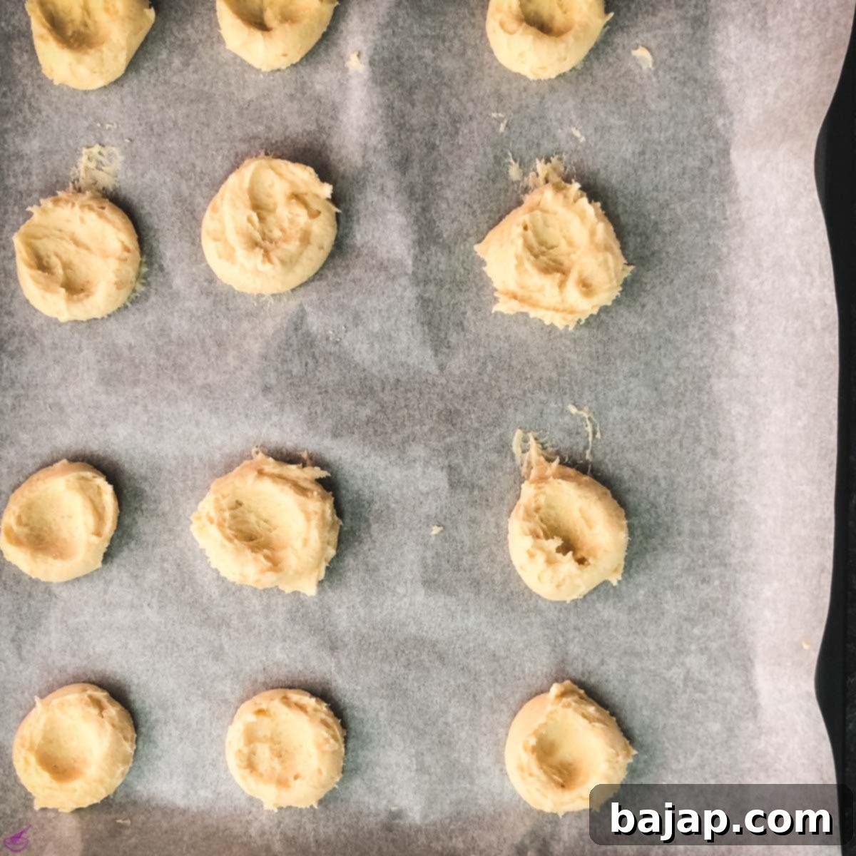 Press the dough balls using your fingers or thumb to make them flatter. This way you can place the Hershey kisses easily on top of the hot cookies after baking.