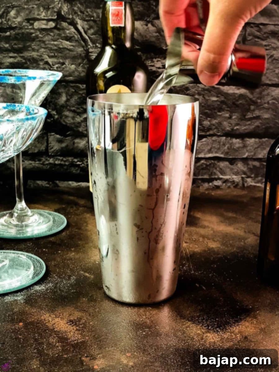 Adding Cointreau, the orange liqueur, to the cocktail shaker.