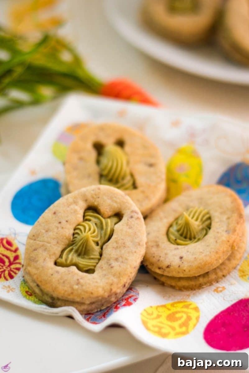 Gorgeous cut out Easter cookies with pistachio ganache placed on Easter napkin.