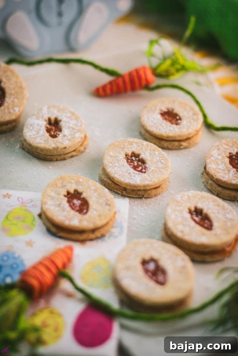 More gorgeous vegan Easter cut-out cookies with apricot jam, elegantly presented on a white stone plate for a festive display.