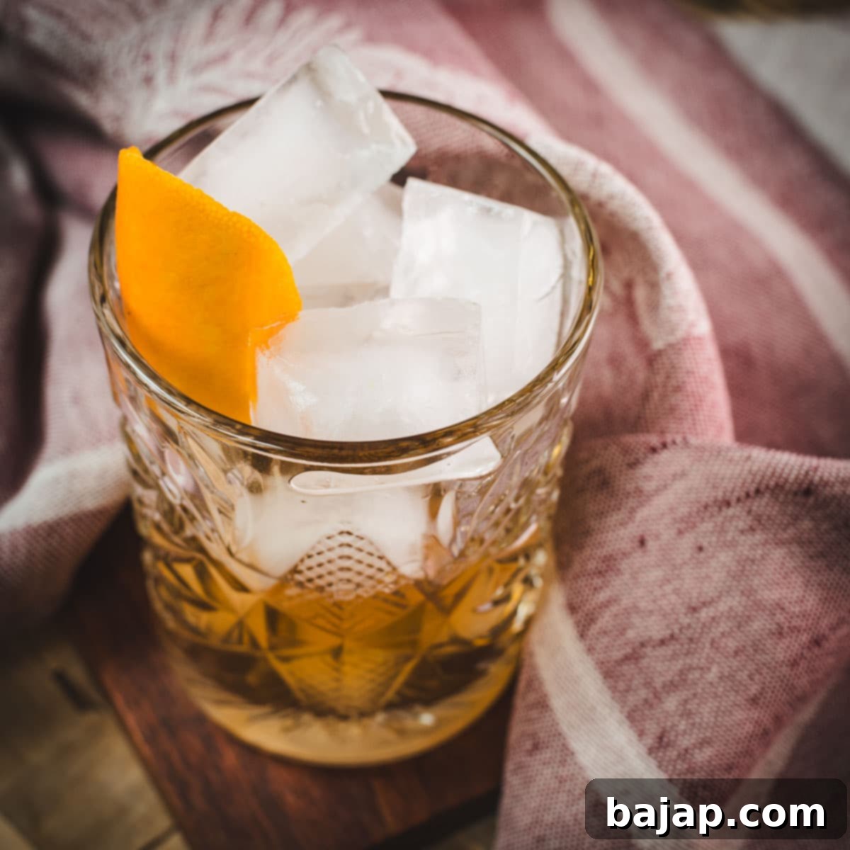 Celebrate National Cocktail Day March 24th 23 Gorgous glass filled with a delicious old fashioned drink. Placed on wooden coaster.