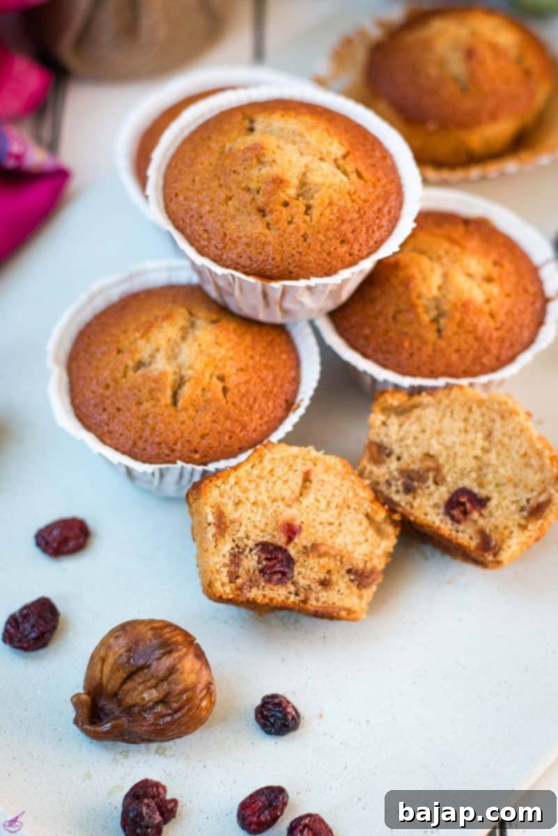 Freshly baked fruit cake muffins on a white plate, showcasing their golden-brown tops and fruit-filled interior.