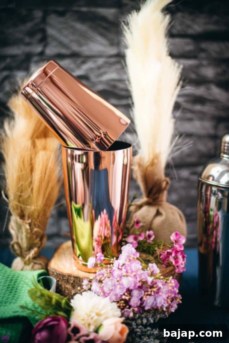Elegant rosé Boston shaker resting on a rustic wooden slice, surrounded by delicate flowers, symbolizing sophisticated cocktail crafting.