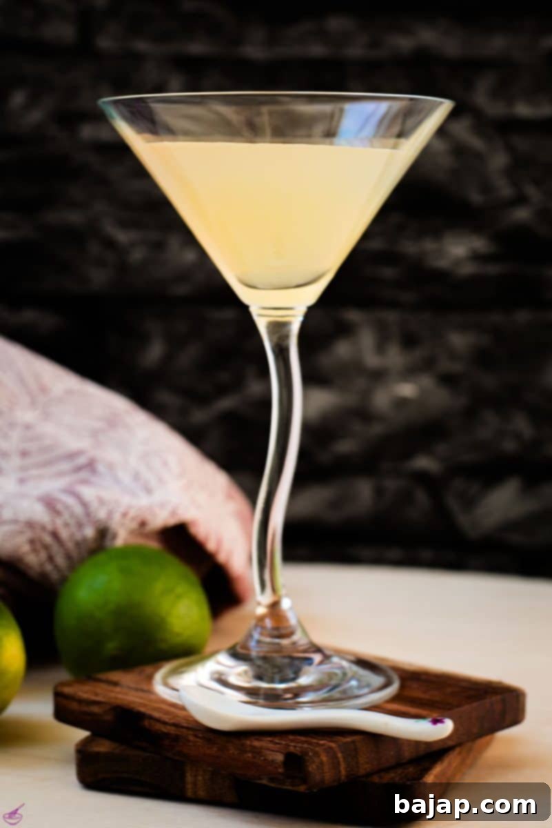 Gorgeous colored daiquiri in cocktail glass. Placed on a wooden board and dark wooden coaster. This classic rum cocktail is perfectly balanced with lime and simple syrup.