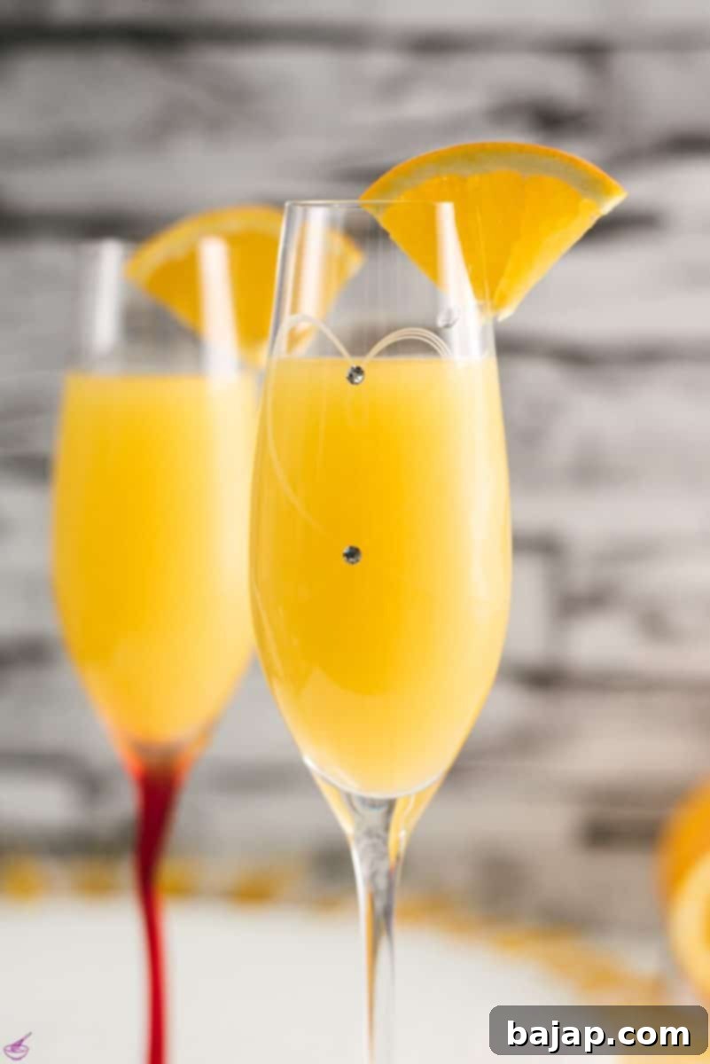 Gorgeous mimosa, garnished with orange slice in cute glass with small gems.