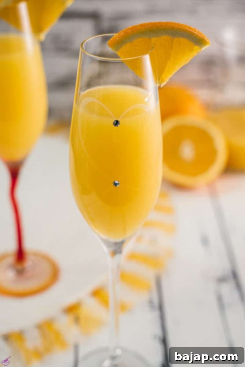 A stunning, perfectly prepared mimosa, garnished with a fresh orange slice and served in an elegant champagne flute with delicate decorative gems. A refreshing brunch drink.