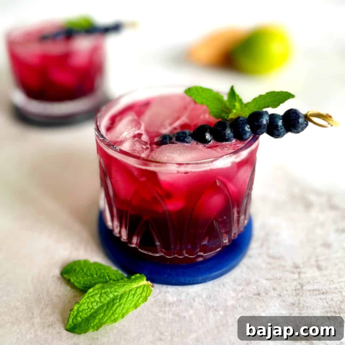 A delightful Blueberry Gin and Tonic cocktail, showcasing fresh blueberries and a lime garnish.