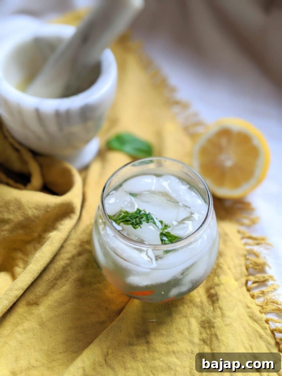 A refreshing Lemon Basil Gin and Tonic garnished with a basil sprig and lemon slices, perfect for a crowd.