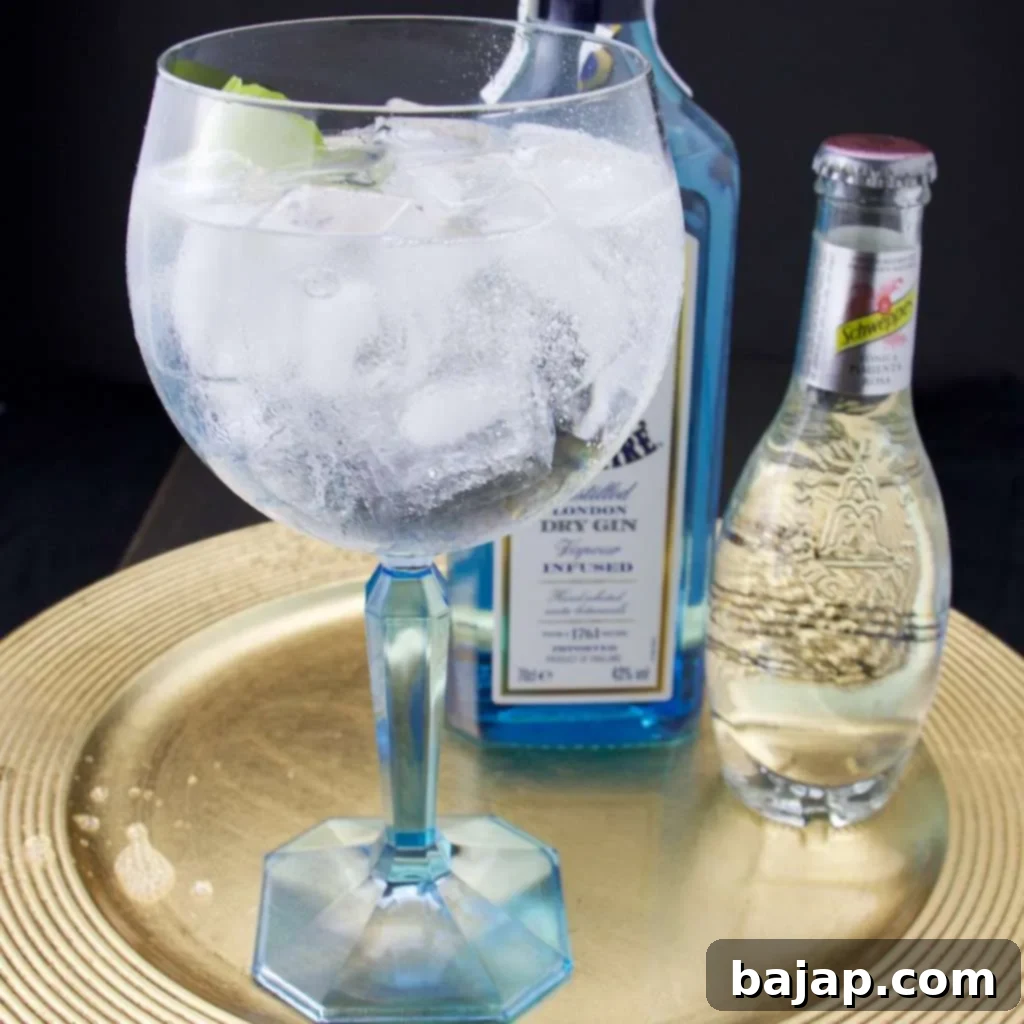 A vibrant Pink Pepper Gin Tonic garnished with pink peppercorns and a lime wedge, in a highball glass.