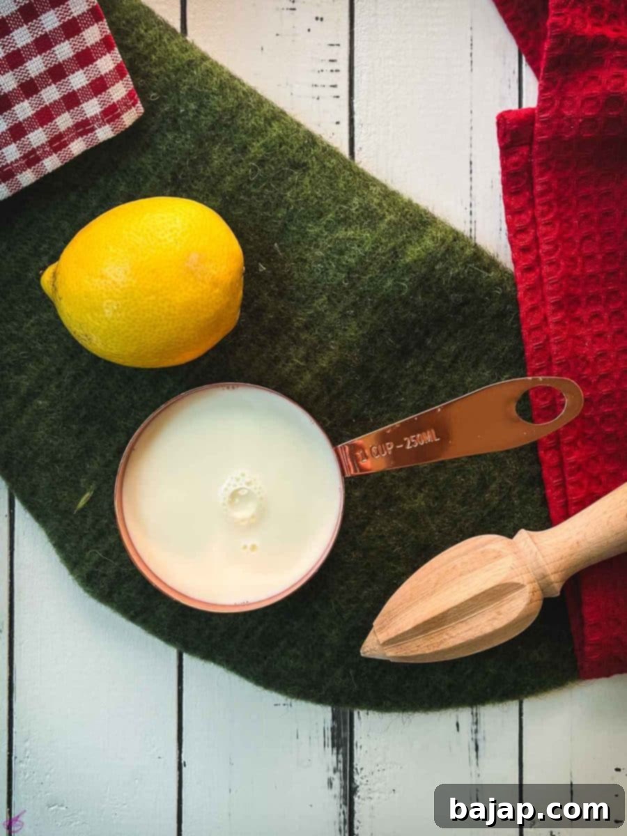 Fresh lemon and a glass of whole milk, the two essential ingredients for making homemade sour milk, placed on a wooden surface.