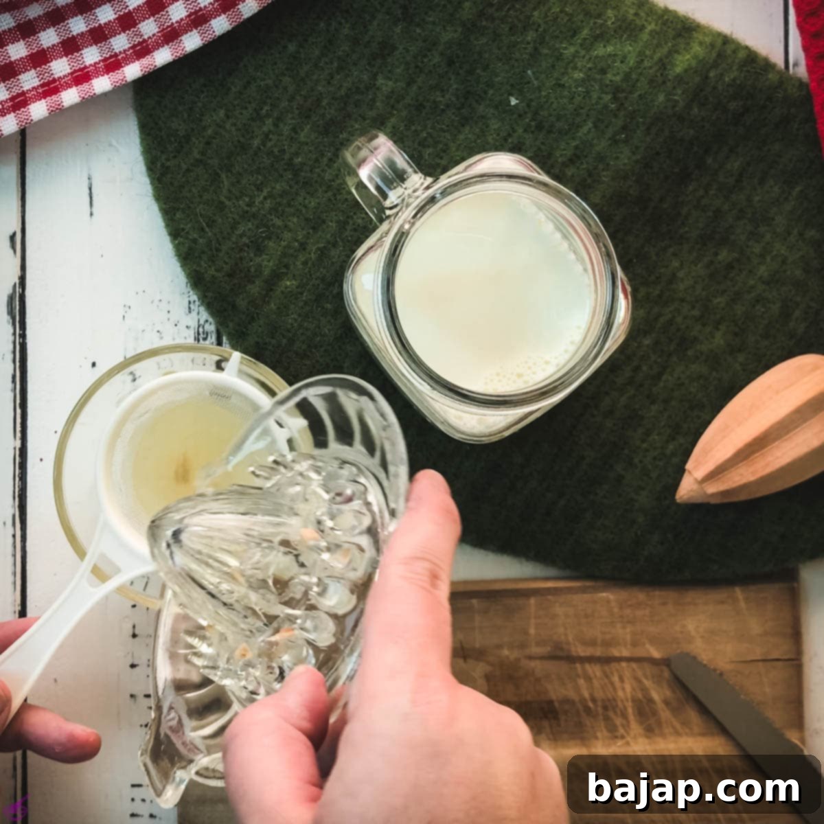 Straining fresh lemon juice through a fine-meshed sieve into a small bowl, ensuring no pulp or seeds for clean sour milk.