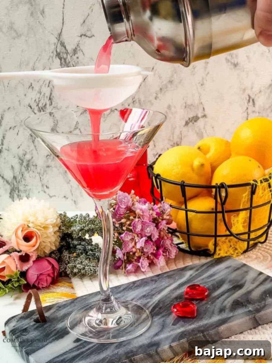 The process of fine-straining a freshly shaken raspberry lemon drop martini into a elegant, chilled cocktail glass to ensure a perfectly smooth beverage.