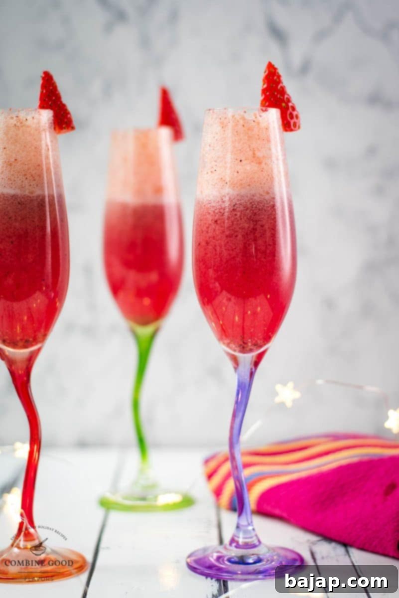 Gorgeous colored champagne flutes filled with vibrant berry mimosa, garnished with fresh strawberries.